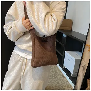 Detail of a brown knit crossbody bag featuring a textured weave and elegant horn button
