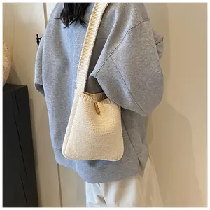 Close-up of cream knit shoulder bag featuring a rustic wooden toggle button closure