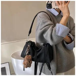Detail einer schwarzen Nylon-Umhängetasche mit braunem Teddy-Plüschtier am Model