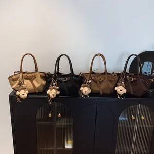 Bolsos de gamuza sintética en cuatro colores con asas de cuero y colgantes de ositos