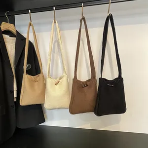 Minimalist knitted crossbody bags with horn buttons in neutral earth tones hanging on hooks