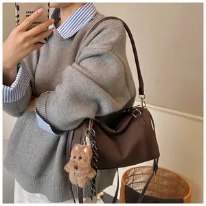 Detail einer dunkelbraunen Retro Boston Bag mit Plüschhund und doppelten Trageriemen