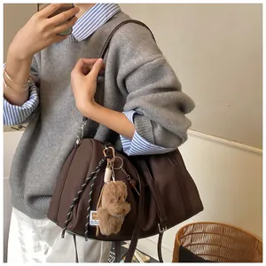 Detail der kaffeebraunen Tote Bag mit Plüschbären-Anhänger und verstellbarem Gurt