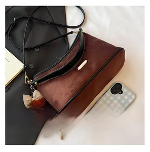 Detail of a brown suede shoulder bag with black leather trim and a cute plush bear charm