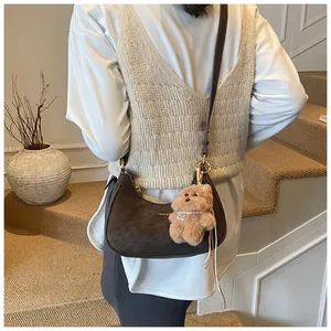 Detail of vintage brown suede crescent shoulder bag with cute plush bear charm