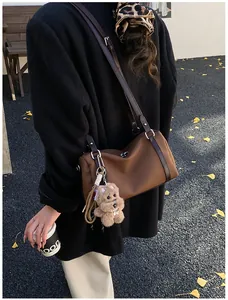 Detail der braunen Vintage-Tasche mit Wildlederoptik und süßem Plüschtier-Anhänger