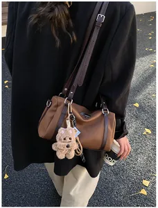 Braune Boston-Tasche aus Leder mit Plüschbär-Anhänger und herbstlichem Hintergrund