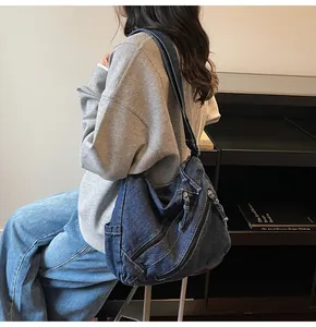 Detail of a large dark blue denim hobo bag with zip pockets and structured texture