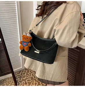 Close-up of black suede underarm bag featuring a cute brown plush bear charm detail