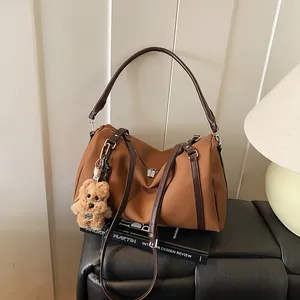 Retro braune XL-Tote-Bag mit Bärenanhänger auf einer Bank in minimalistischem Raum