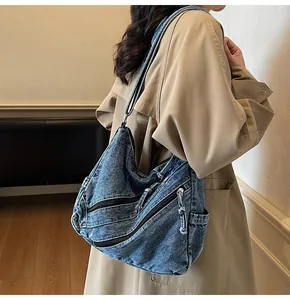Detailed macro of vintage blue washed denim shoulder bag with functional metal zippers