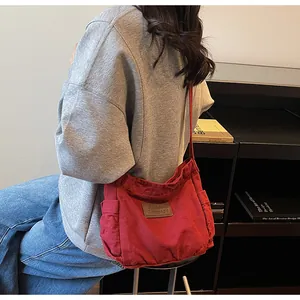 Detail of red canvas crossbody bag showing side pocket and brown leather brand label