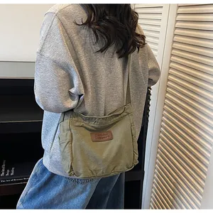Detail view of military green canvas crossbody bag featuring side pocket and leather patch