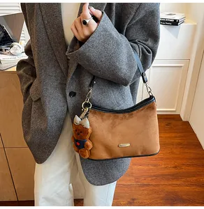 Detail of a brown suede hobo bag with leather trim and a cute plush bear charm