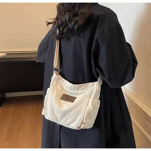 Detail view of the side pocket and adjustable strap on the off-white canvas crossbody bag