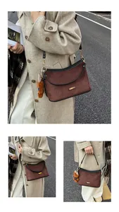 Close-up of brown suede bag with black leather trim and a cute plush bear charm