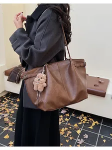 Brown leather tote bag with a cute bear charm, styled for autumn outdoor activities