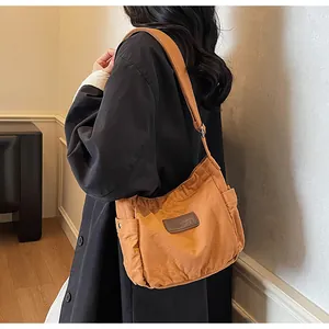 Detailed close-up of yellow canvas shoulder bag with a brown leather logo patch and side pocket