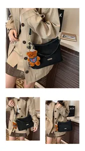 Detail of black leather underarm bag with cute plush bear pendant and gold metal hardware