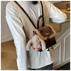 Detail of suede mini backpack featuring faux fur trim and cute rabbit pendant on back