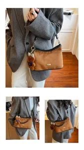 Detail of brown suede underarm bag with black leather trim and cute plush bear charm