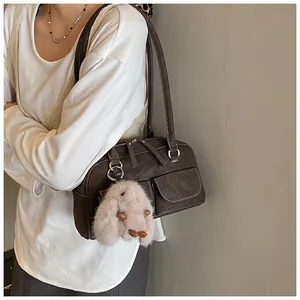 Close-up of vintage brown leather boston bag with external pockets and plush bunny charm
