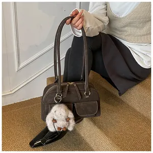 Detail of retro dark brown suede bag with white contrast stitching and plush bunny charm