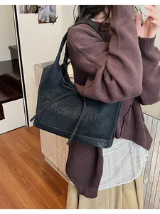 Detail of vintage black tote bag featuring embossed logo and delicate leather ribbon bow