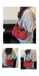 Detail of red canvas crossbody bag with brown leather label and drawstring pleats