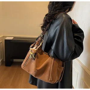 Sac à bandoulière marron rétro avec breloque ours montrant le profil latéral détaillé
