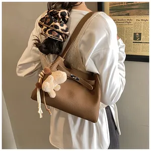 Brown litchi leather bucket bag with silver twist lock and plush puppy charm detail