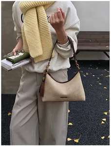 Close-up of hobo bag featuring premium beige suede material and leather tassel detail