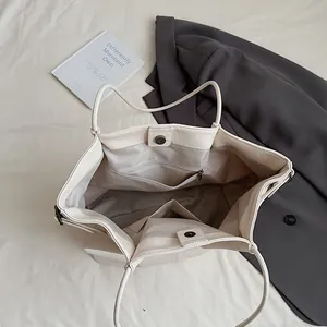Minimalist off-white leather tote bag with interior pockets and magnetic closure