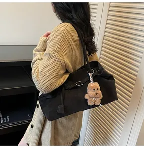 Detail einer großen schwarzen Ölwachs-Ledertasche mit niedlichem braunem Bärenanhänger