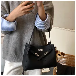 Detail of black pebbled leather handbag with metal buckle and plush puppy keychain