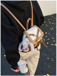 Detail view of mini faux fur suede backpack with plush bunny charm on model's back