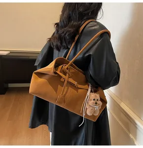 Detail der Vintage-Tote-Bag in Karamell mit Bärenanhänger an einem weiblichen Model