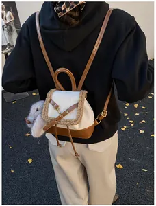 Rear view of a suede mini backpack with plush trim and rabbit charm in autumn setting