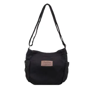 Minimalist black canvas crossbody bag with adjustable strap and leather fashion label