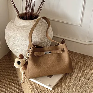 Minimalist brown pebbled leather bucket handbag with metal buckle and plush puppy charm