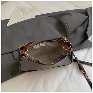 Detalle de bolso de cuero marrón con cremallera dorada y forro de tela en espiga gris