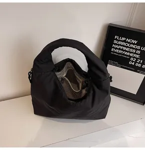 Detail view of the black nylon tote bag interior with striped lining and zipper pocket