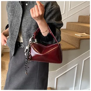 Detailaufnahme der weinroten Boston-Tasche aus Leder mit Metallringen und Kordel-Akzenten