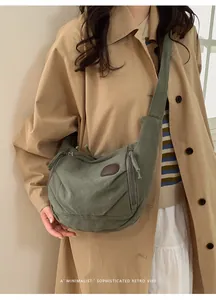 Detail of army green nylon crescent bag with wide strap and brown leather patch