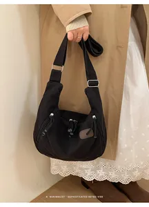 Detail of black nylon dumpling bag featuring multiple zip pockets and adjustable strap
