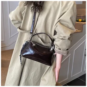 Detail der dunkelbraunen glänzenden Boston Bag getragen zu einem khakifarbenen Trenchcoat