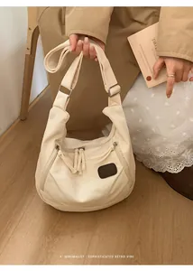 Detailed close-up of retro cream canvas half-moon bag featuring adjustable shoulder strap