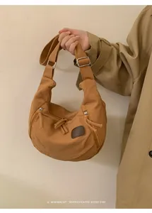 Detail view of khaki nylon crescent bag with leather patch and wide shoulder strap