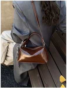 Detail der dunkelbraunen Lackleder-Handtasche mit glänzender Textur und Anhänger