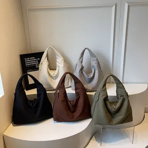 Collection of large nylon hobo bags in five colors on a minimalist white display
